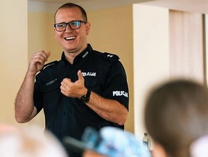 Na zdjęciu widać uśmiechniętego policjanta, który uczy dzieci i przypomina dzieciom zasady bezpieczeństwa