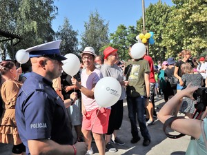 policjant stoi przed grupą osób podczas koncertu Powiatowy Blues, w ręku trzyma balona