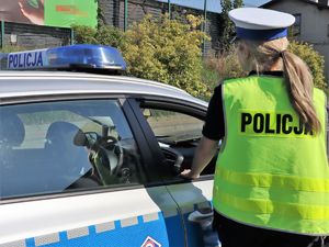 policjantka stoi obok policyjnego radiowozu