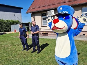 obok policjantów stoi pies Sznupek