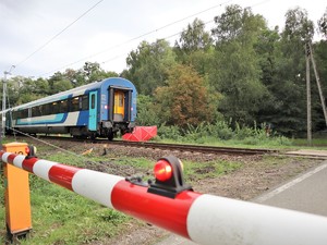 na zdjęciu widać zatrzymany pociąg osobowy i zamknięte rogatki