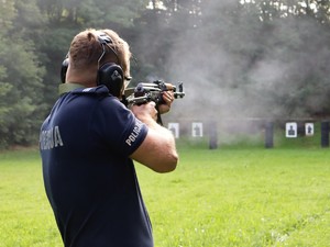 policjant strzela z broni długiej do tarczy