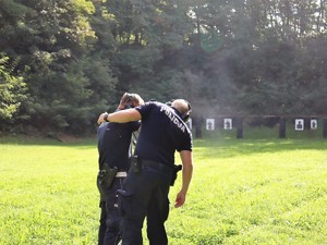 policyjny instruktor strzelań sprawdza broń policjantowi po zakończeniu strzelania