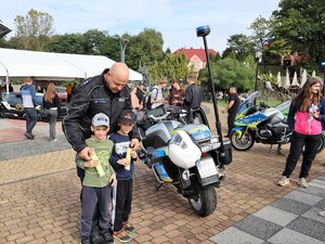 policjant pozuje do wspólnego zdjęcia z dwoma chłopcami, którzy trzymają w rękach odblaski