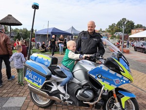 policjant stoi obok motocykla, na motocyklu siedzi dziecko