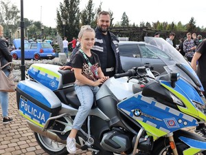 policjant stoi obok motocykla, na motocyklu siedzi dziecko