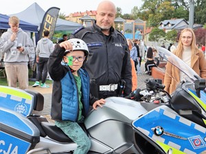 policjant stoi obok motocykla, na motocyklu siedzi dziecko