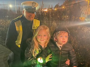 do wspólnego zdjęcia pozuje policjant i dzieci, które trzymają odblaski