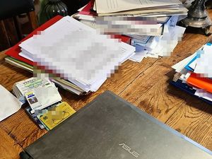 na stole leży laptop oraz różne dokumenty