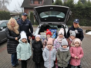 na zdjęciu widać przedszkolaki oraz policjantów, którzy wspólnie pozują do zdjęcia przy radiowozie