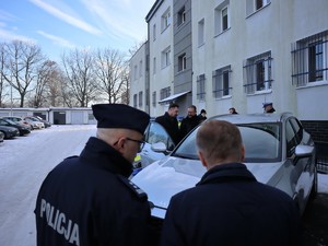samorządowcy oglądają nowo zakupiony policyjny radiowóz, prezentuje go Komendant Powiatowy