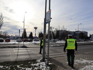 policjanci stoją przy przejściu dla pieszych, obserwują ruch samochodów