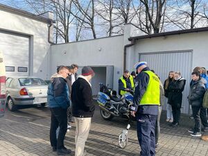 policjant prezentuje praktykantom sposób prowadzenia oględzin na miejscu wypadku