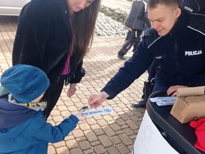 policjant wręcza dziecku odblask