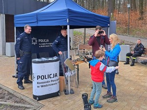 przed policyjnym stoiskiem osoby testują narkogogle, uśmiechają się do policjantów