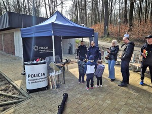 policjant uśmiecha się do stojących przed nim dzieci podczas wydarzenia sportowego