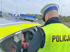 policjant stoi obok radiowozu