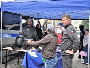 chłopiec celuje z broni, stoi obok funkcjonariusza służby więziennej