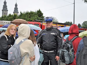 policjant pozuje do zdjęcia, stoi pośród młodzieży i uśmiecha się