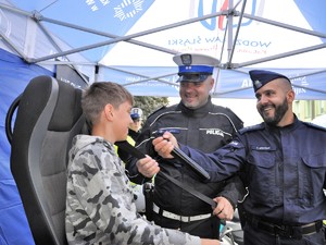 chłopak siedzi na symulatorze zderzeń, rozmawiają z nim policjanci