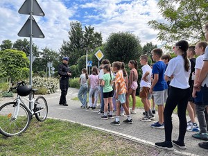 policjant stoi przed grupą dzieci podczas egzaminu na kartę rowerową