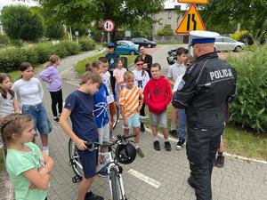 policjant stoi przed grupą dzieci podczas egzaminu na kartę rowerową