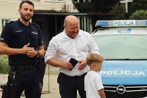 policjant pozuje do zdjęcia z Zastępcą Prezydenta Miasta Wodzisławia Śląskiego i chłopcem