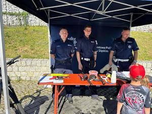 policjanci podczas festynu stoją przy stoisku profialktycznym