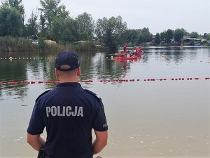 policjant stoi na brzegu kąpieliska, trwa akcja poszukiwawcza