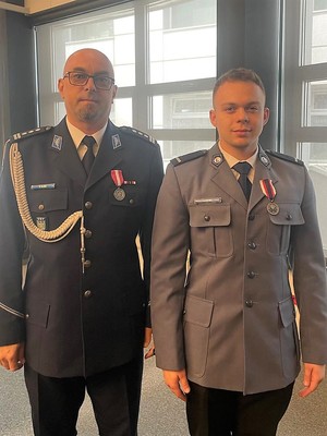 Zdjęcie przedstawia dwóch policjantów w galowych mundurach z medalami przypiętymi do piersi