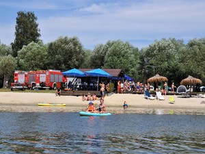 na plaży stoją ratownicy wodni oraz plażowicze