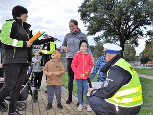 policjant rozmawia z uczestnikami akcji Jak dobrze cię widzieć i rozdaje odblaski