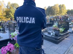 zdjęcie przedstawia sylwetkę policjanta na tle cmentarza