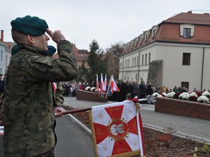 żołnierz pod pomnikiem oddaje honor, przedstawiciele służb mundurowych składają pod pomnikiem kwiaty