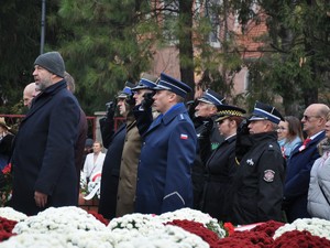 przedstawiciele służb mundurowych składają pod pomnikiem kwiaty