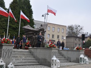 przedstawiciele służb mundurowych składają pod pomnikiem kwiaty