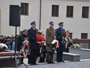 przedstawiciele służb mundurowych składają pod pomnikiem kwiaty