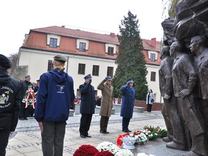 przedstawiciele służb mundurowych składają pod pomnikiem kwiaty