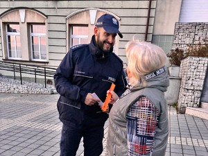 policjant przekazuje kobiecie odblaskową opaskę