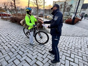 policjant wręcza rowerzyście odblask