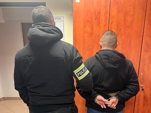 policjant trzyma zatrzymanego meżczyznę