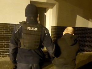 policjant stoi obok zatrzymanego mężczyzny