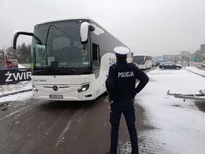 policjant stoi przed autobusem turystycznym