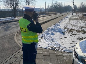 policjant stoi przy drodze i kontroluje prędkość pojazdów