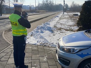 policjant stoi przy drodze, obserwuje ruch pojazdów