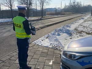 policjant stoi przy drodze, obserwuje ruch pojazdów