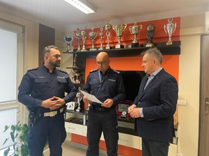 obok Komendanta stoi policjant i przedstawiciel stowarzyszenia biegłych z zakresu motoryzacji