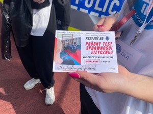 kobieta trzyma w dłoni ulotkę o rekrutacji do służby w Policiji