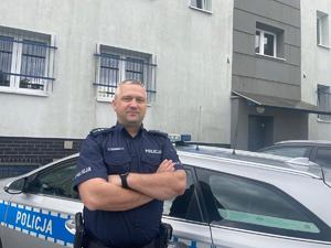 policjant stoi przed radiowozem