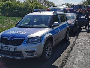 policyjny radiowóz a za nim wozy strażackie w trakcie interwencji przy zbiorniku wodnym